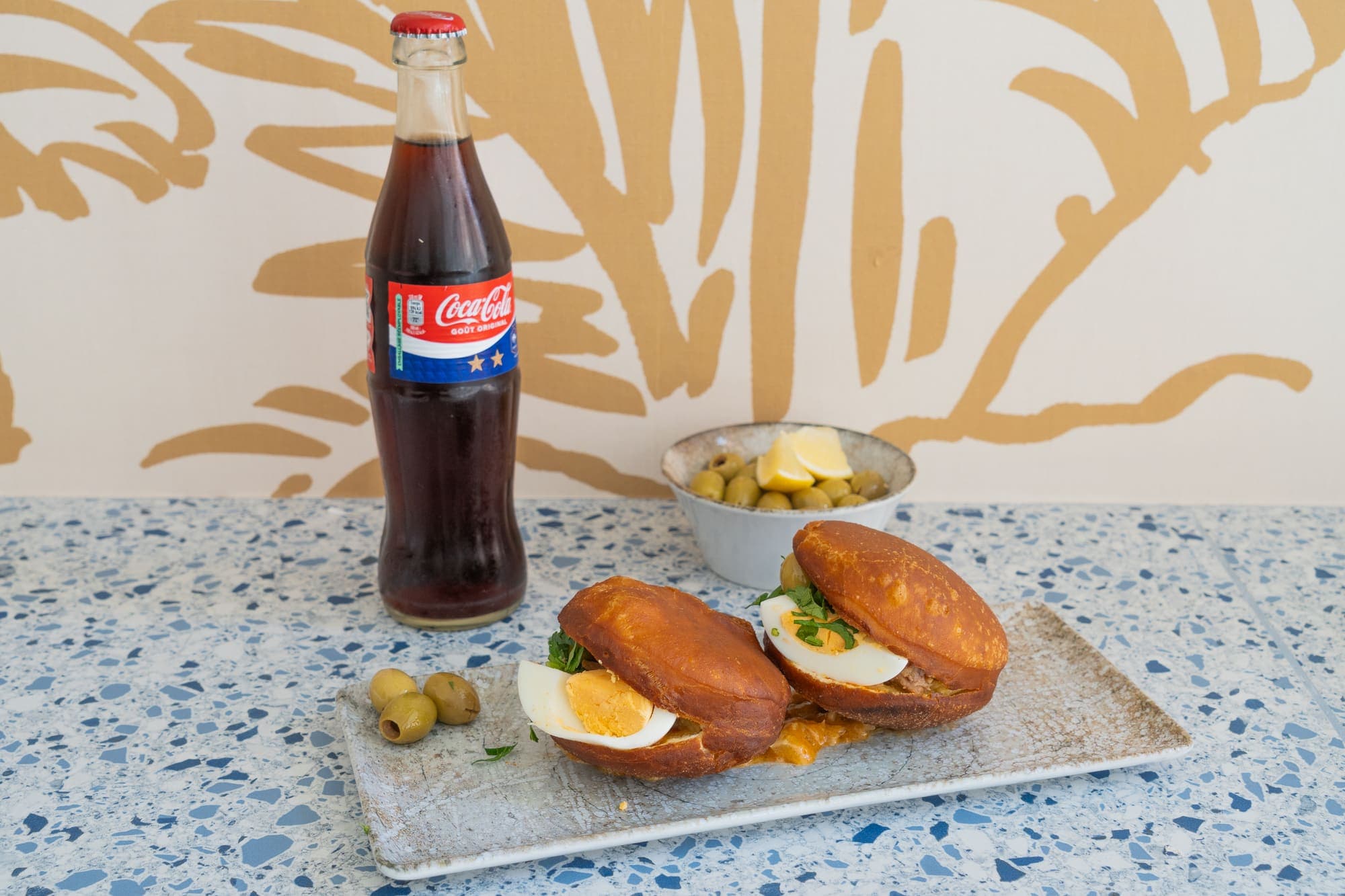 Bouteille de Coca-Cola et sandwichs bricks garnis d’oeuf et d’olives.