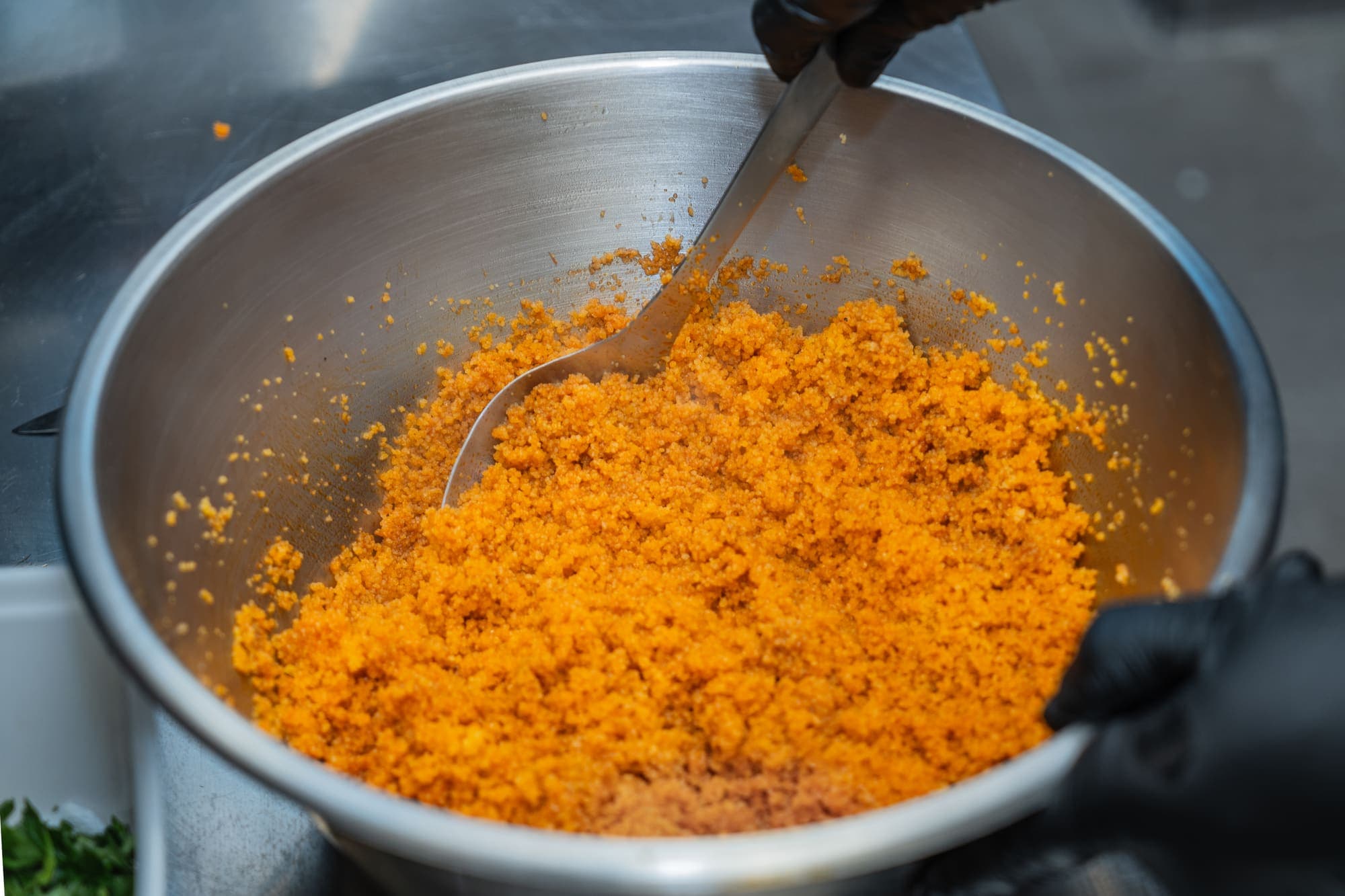 Semoule de couscous travaillée à la main dans un grand saladier en inox.